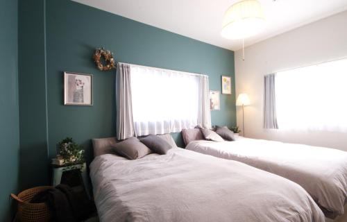 名古屋Guest House Re-worth Joshin1 3F的配有两张床铺的蓝色墙壁和窗户
