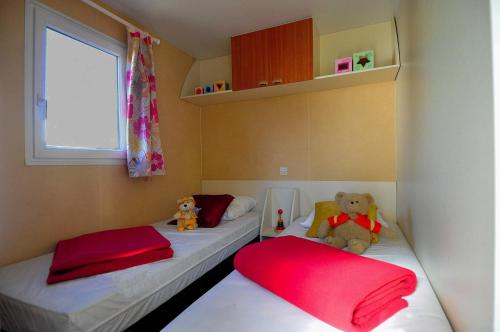圣吕奈尔拉图埃斯宿营地酒店的一个小房间设有两张床,上面有泰迪熊