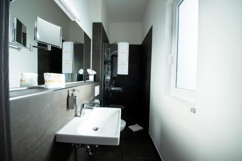伯布林根V Boutique Hotel Böblingen的浴室设有白色水槽和镜子