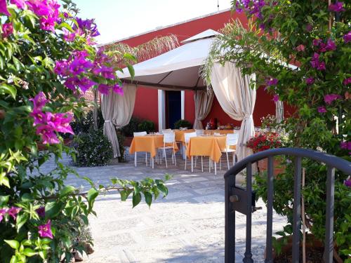 马利耶Mediterraneo B&B的一个带桌子、白色遮阳伞和鲜花的庭院