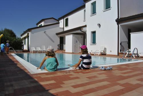 卡奥莱Residence Tamerici的两个孩子坐在游泳池边