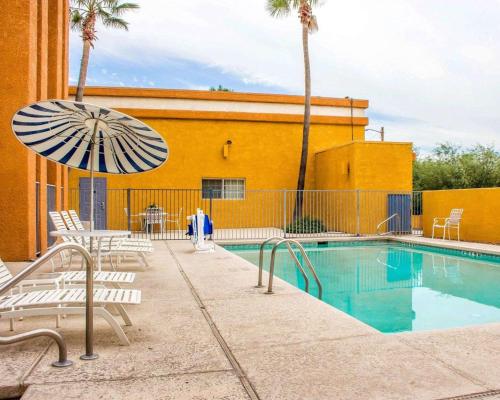土桑品质酒店  - 图森机场的一座带椅子和遮阳伞的游泳池位于大楼旁