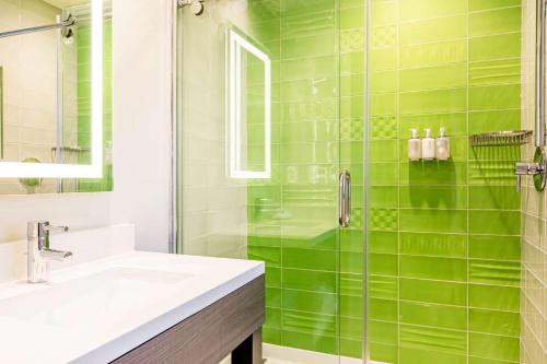 洛杉矶Rodeway Inn near Melrose Ave的绿色瓷砖浴室设有水槽和淋浴