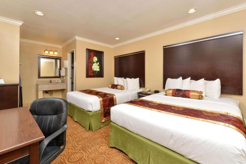 圣地亚哥Rodeway Inn San Diego Mission Valley/SDSU的酒店客房配有两张床和一张书桌