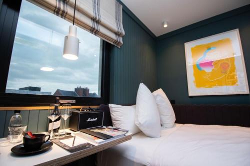 都柏林The Devlin Dublin的酒店客房配有一张床、一张书桌和一台笔记本电脑