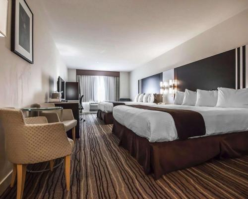 里士满品质酒店－机场南部　的酒店客房带两张床和一张桌子以及椅子。