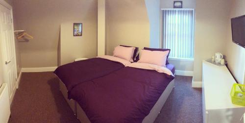 塞尔比Micklegate House的一间卧室配有一张带紫色床单的床和窗户。