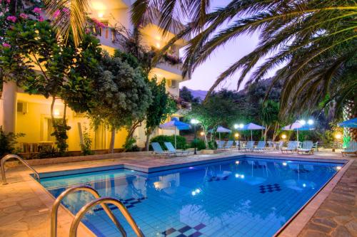 罗达奇诺Sunrise Hotel & Apartments的夜间在酒店前的游泳池