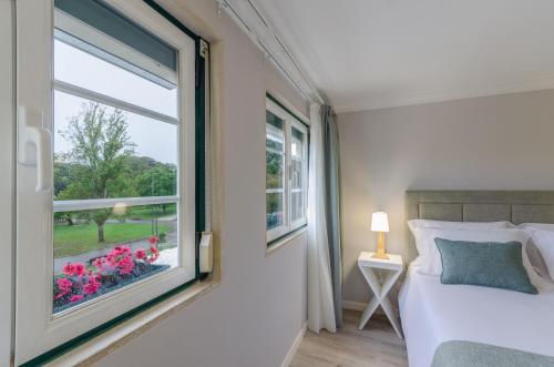里斯本Ver Belém Suites的卧室设有窗户,配有一张床和鲜花