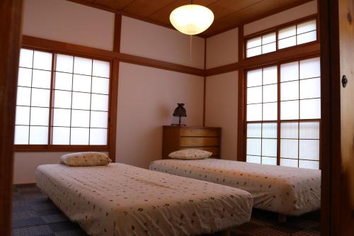 伊东Smart House Oceanview的带2扇窗户的客房内的2张床