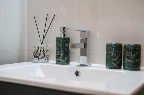 里斯本Lx Design Apartment near Congress Center的浴室柜台配有3个绿色花瓶和水槽