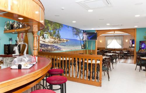 埃尔阿雷纳尔索尔海滩酒店的餐厅设有酒吧,墙上挂着一幅大画