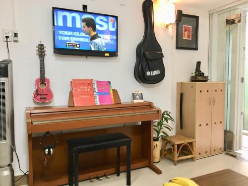 胡志明市Baoanh Hostel的一间设有钢琴和壁挂电视的房间