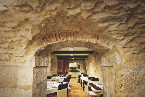昆卡莱昂诺尔德阿基塔尼亚酒店的餐厅设有石墙,配有桌椅