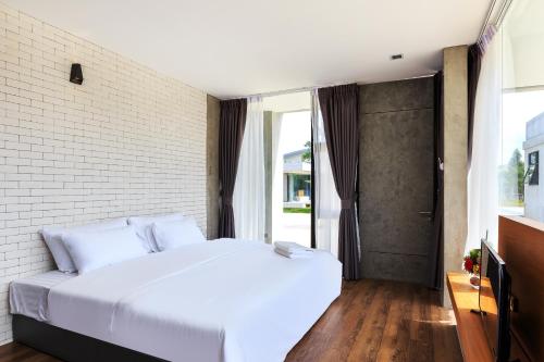 拉廊Sunnyvale Ranong 1的卧室配有白色的床和砖墙