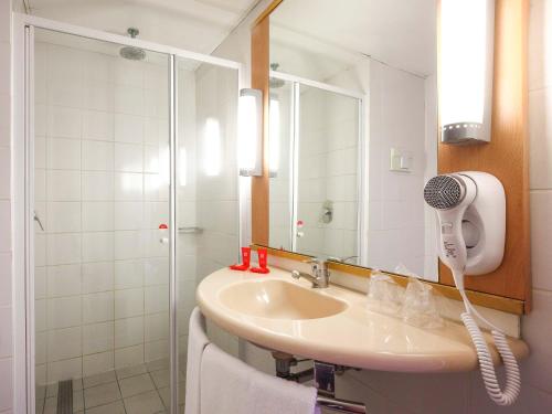 布宜诺斯艾利斯布宜诺斯艾利斯国会宜必思酒店的浴室配有水槽和带吹风机的淋浴