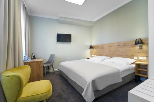 耶莱尼亚古拉多木佐德罗索易酒店的酒店客房带一张大床和一把椅子