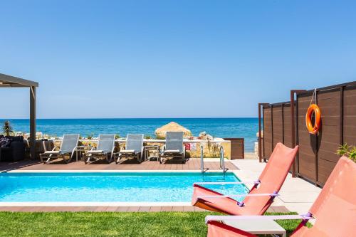 罗希姆诺Espera, Luxury Beach Front Residence, By ThinkVilla的一个带桌椅的海洋游泳池