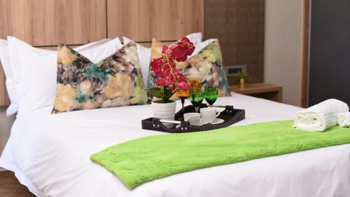 EshoweAloe Lifestyle Hotel的床上的带鲜花和玻璃杯的托盘