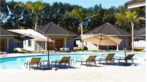 EshoweAloe Lifestyle Hotel的部分房屋旁的游泳池配有椅子和遮阳伞