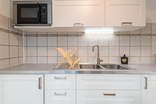 波城Appartement cœur de ville - Wifi - Lave-sèche linge的厨房配有白色橱柜和水槽