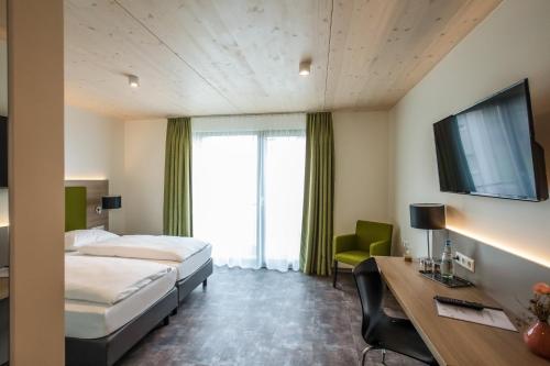 LottstettenHotel Holzscheiter的酒店客房设有两张床、一张桌子和一台电视。