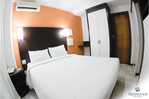维多利亚Triângulo Apart Hotel的卧室配有白色大床和橙色墙壁