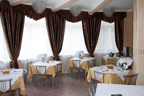 基兹洛沃茨克米沙塔度假村的餐厅设有白色的桌椅和窗户。