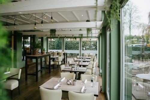 Riethoven仕乐途餐厅酒店的餐厅设有白色的桌椅和大窗户。