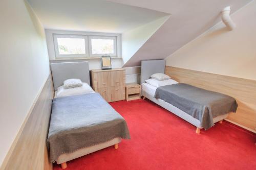 波兹南Botanik Hostel的一间卧室配有两张床,铺有红地毯