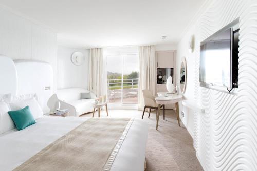 阿尔宗Miramar La Cigale Hotel Thalasso & Spa的一间白色的卧室,配有床和客厅