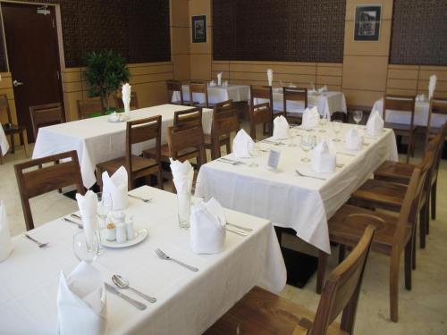 芽庄尼非酒店的用餐室配有白色桌椅和餐巾