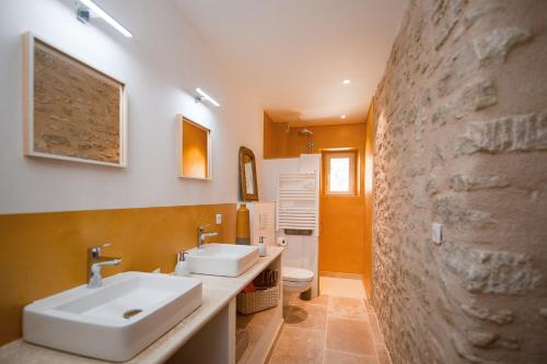 博尼约La Ressence Luberon的一间带两个水槽和石墙的浴室