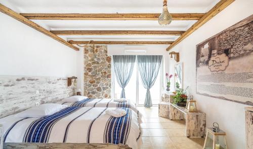 MonólithosLimeri Traditional Guest House的一间卧室设有两张床和石墙