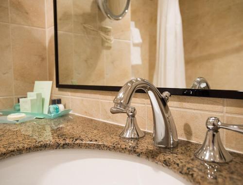 滨湖尼亚加拉君临酒店的浴室水槽设有浴缸和镜子