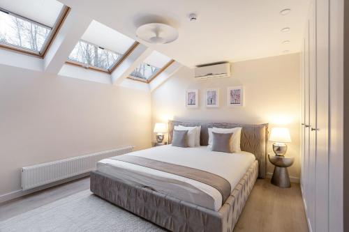 维尔纽斯Luxury for everyone - Hills Park Lux Apartments 1的一间卧室配有一张带白色墙壁和天窗的床。