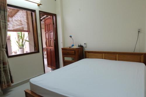 芽庄Moon house tropical garden - East side的卧室配有白色的床和窗户。