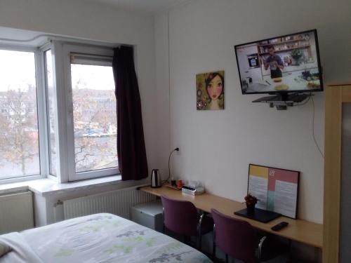 鹿特丹班恩酒店的一间卧室配有书桌、一张床和电视。