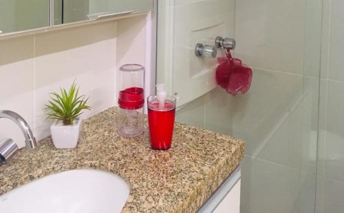 马塞约Apartamento na Ponta Verde Maceió Facilities的浴室水槽和柜台上的红玻璃