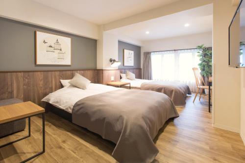 大阪Hotel Replace Namba Osaka的酒店客房设有两张床和一张桌子。