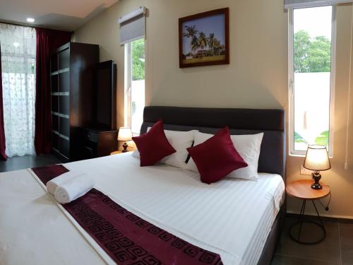 珍南海滩珍南别墅旅馆的卧室配有带红色枕头的大型白色床