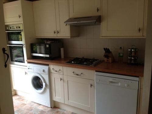 奇平卡姆登Brook Cottage的厨房配有洗衣机和微波炉。
