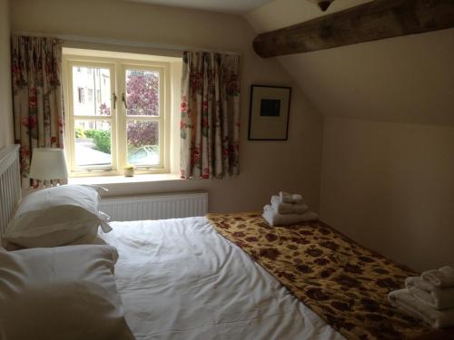 奇平卡姆登Brook Cottage的卧室配有白色的床和窗户