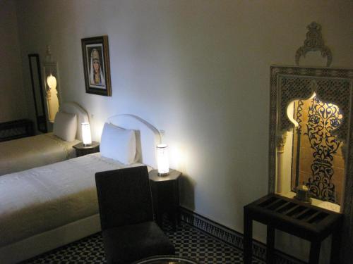 非斯里亚德沙巴酒店的一间卧室配有一张床、一把椅子和镜子