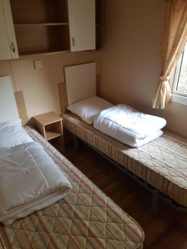 滨海苏拉克Mobil Home Soulac的两张床位于带窗户的房间内