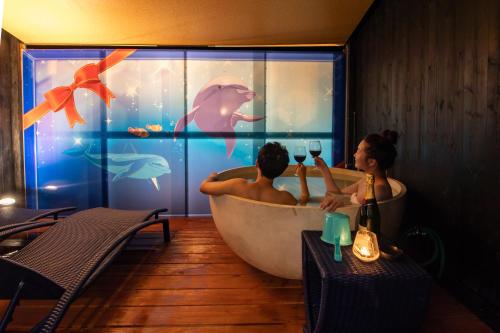 白滨XYZ私人Spa中心及海滨度假酒店 的男人和女人在带鱼缸的浴缸里