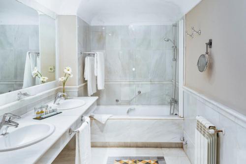 梅里达梅里达旅馆的白色的浴室设有2个盥洗盆和1个浴缸。