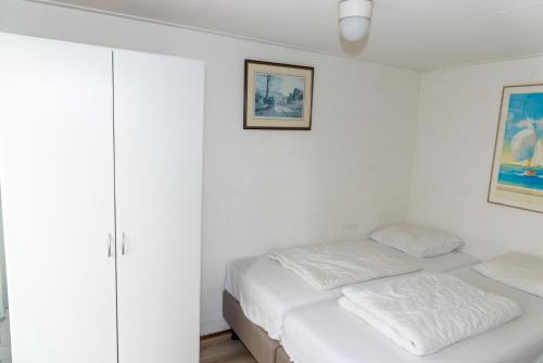 布雷斯肯斯Hello Zeeland - Vakantiehuis Duinroos 167的一间白色卧室,配有床和橱柜