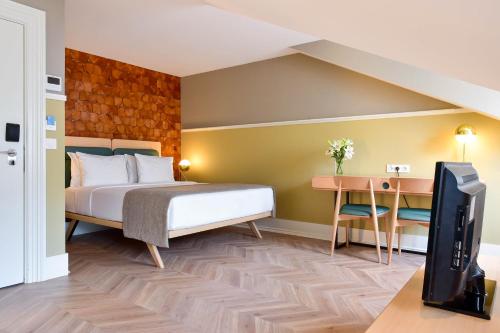 里斯本我的故事特茹酒店的一间卧室配有一张床、一张书桌和一台电视。