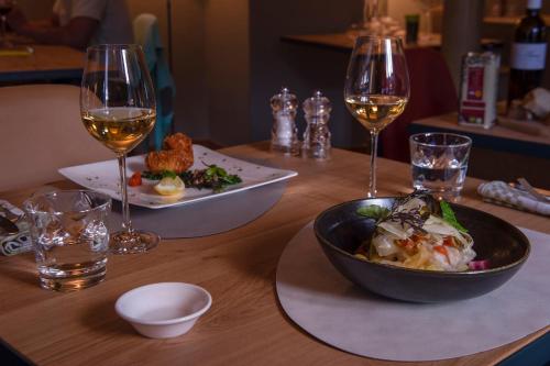 阿尔隆Hostellerie du Peiffeschof, The Originals Relais (Relais du Silence)的一张桌子,上面放着一碗食物和两杯葡萄酒